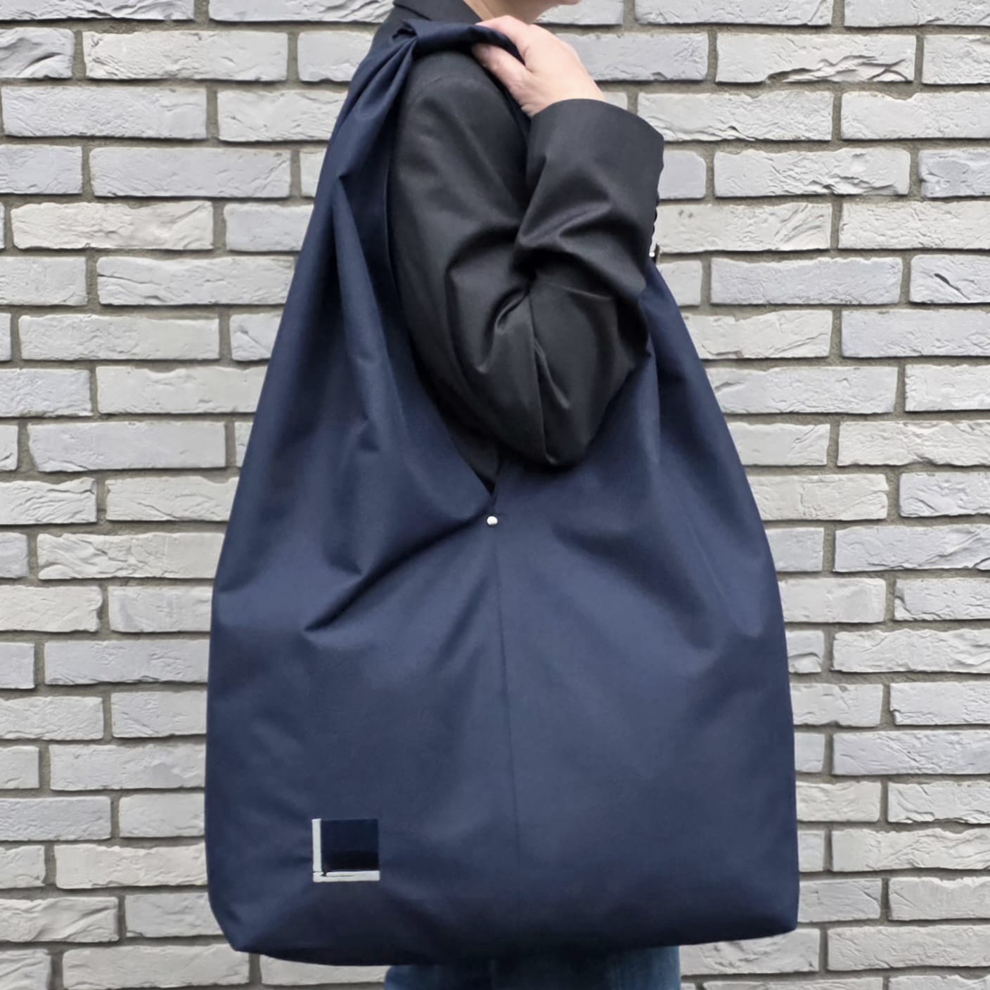 Woman wearing handmade navy blue hobo bag, minimalist water-resistant tote for everyday use from Rimalinum