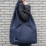 Woman wearing handmade navy blue hobo bag, minimalist water-resistant tote for everyday use from Rimalinum