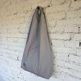 Light grey waterproof hobo tote bag hanging on wall – unisex handmade design