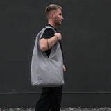 Man carrying large light grey unisex waterproof hobo bag – everyday minimalist tote