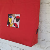 Detail of abstract geometric embroidery and red cotton fabric on statement tote bag