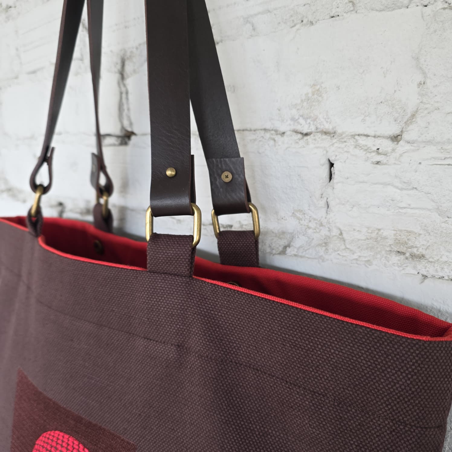 Close-up of leather handles and red interior lining of handmade tote bag