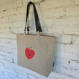 Large natural linen tote bag with embroidered floral design hanging on a wall